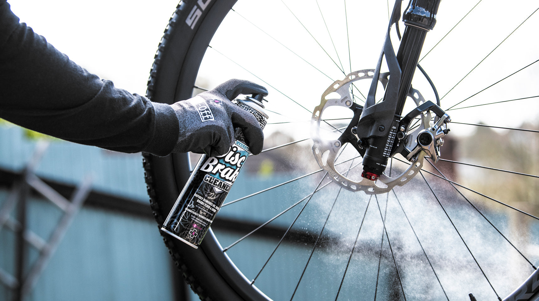 Muc-Off Disc Brake Cleaner applied to a bicycle disc rotor