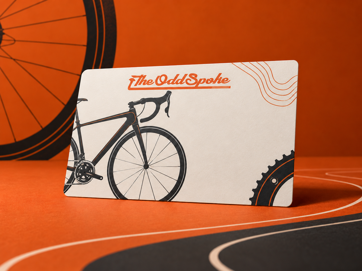 The Odd Spoke gift voucher card featuring the official orange script logo, a road bike illustration and burnt orange background
